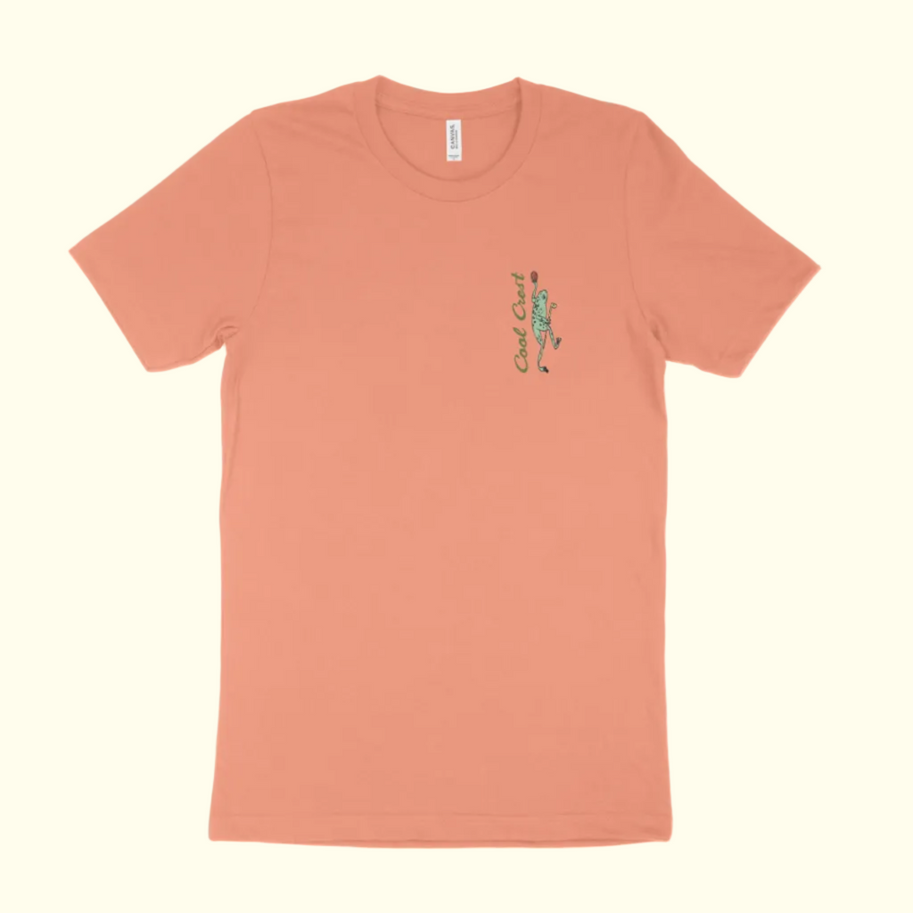 Peach-colored t-shirt with a green graphic on a white background